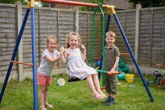 Groupe d'enfants souriants sur une balançoire de jardin