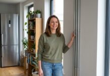 Rendre votre foyer plus écologique avec le conduit 3cep Femme souriante près d'un conduit moderne dans un salon