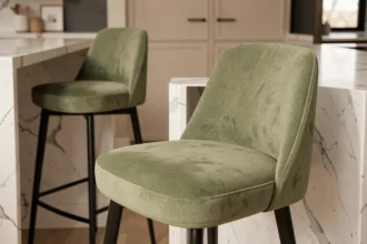 Housse de tabouret de bar en velours vert sauge sur un tabouret moderne dans une cuisine contemporaine au comptoir en marbre blanc