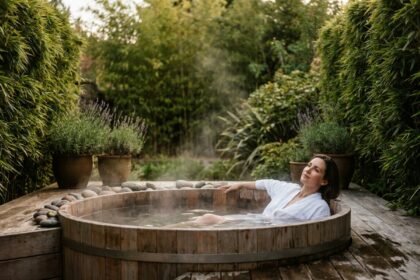 Femme se relaxant dans un bain à remous en bois entouré de bambous et lavande dans un jardin privé aménagé en espace spa